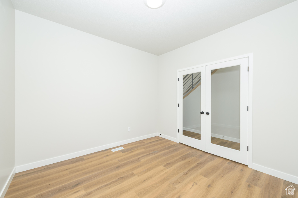 Spare room featuring baseboards, french doors, and light wood-style floors