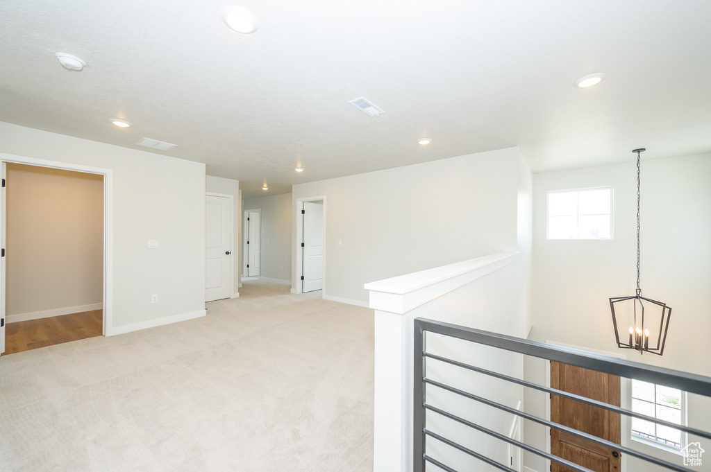 Spare room with light carpet, baseboards, recessed lighting, and a chandelier