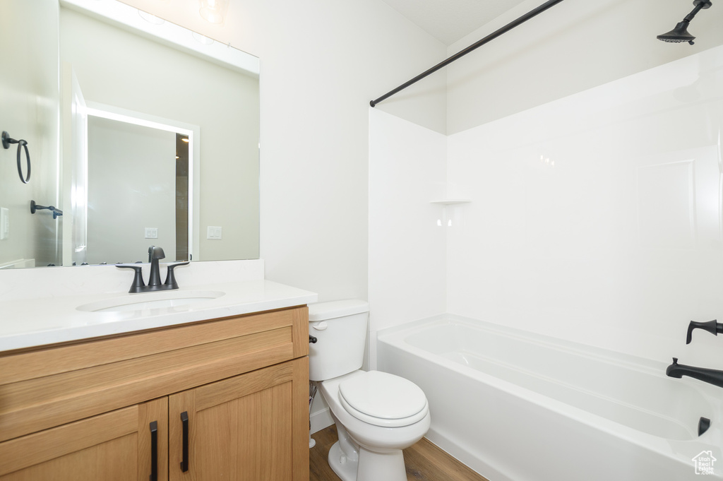 Full bathroom featuring toilet, washtub / shower combination, vanity, and wood finished floors