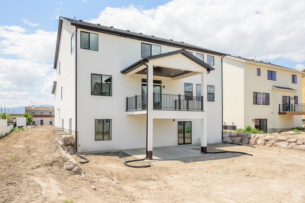 Rear view of property featuring a balcony, stucco siding, and a patio