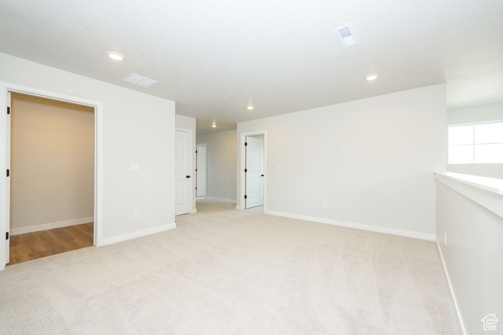 Spare room featuring light carpet, baseboards, and recessed lighting