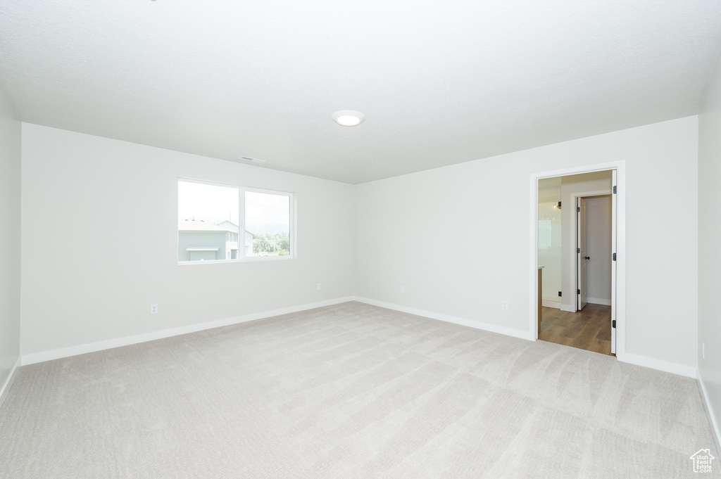 Spare room featuring light colored carpet and baseboards