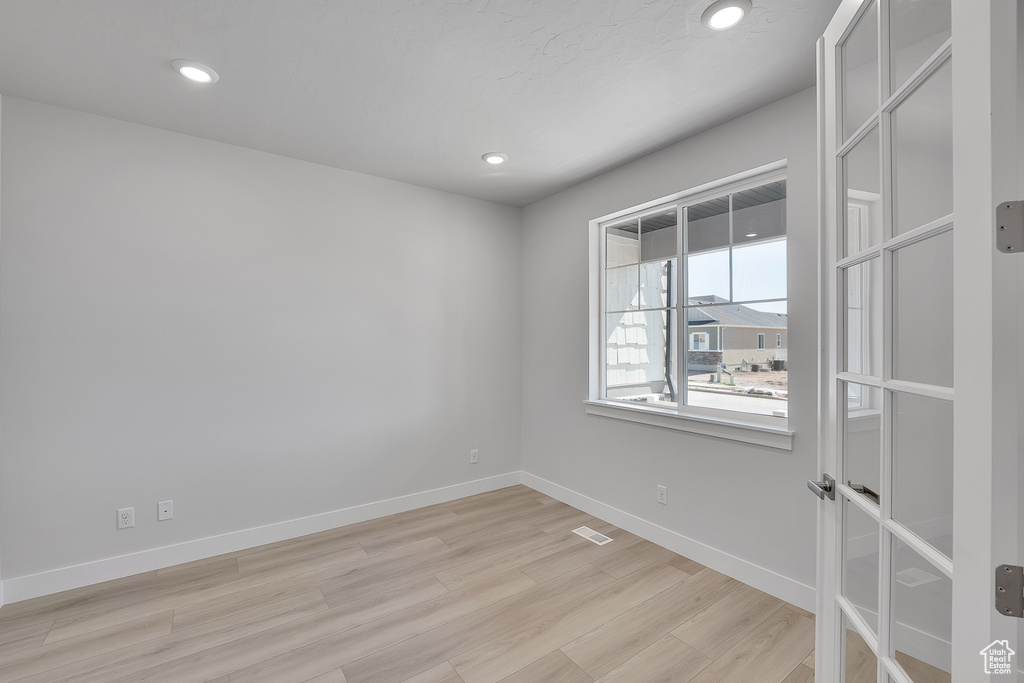 Spare room featuring light wood finished floors, baseboards, and recessed lighting