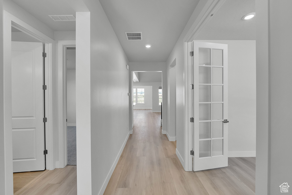 Hall featuring light wood-style floors, baseboards, and recessed lighting