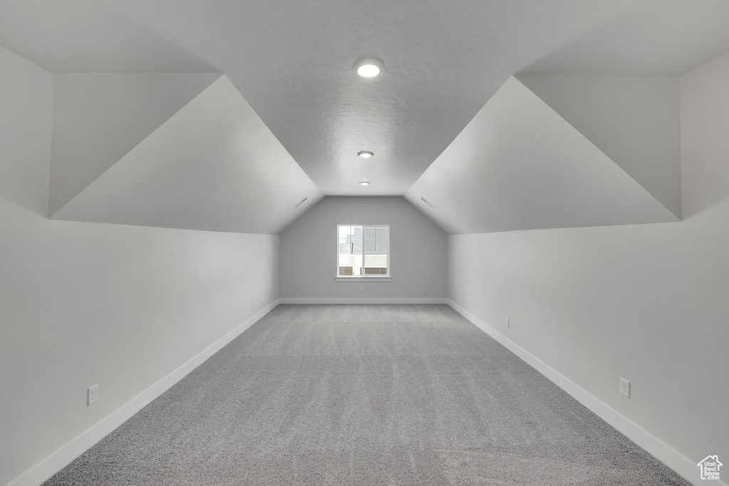 Additional living space with light carpet, baseboards, lofted ceiling, and recessed lighting