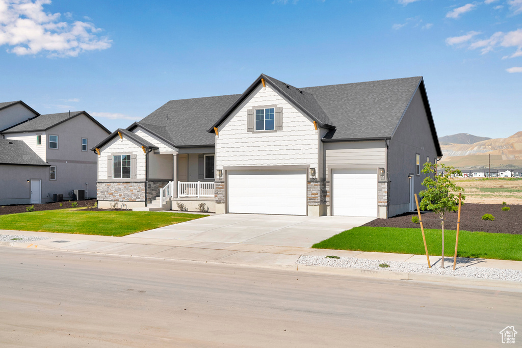 View of front of property with an attached garage, stone siding, driveway, and roof with shingles