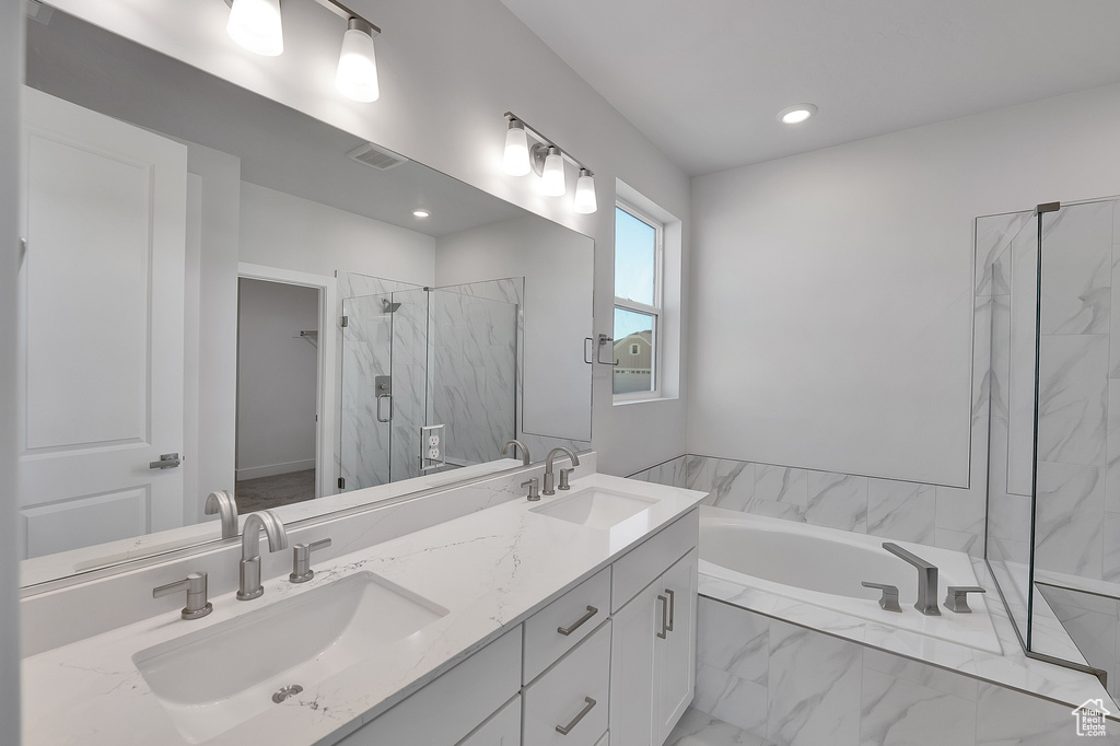 Bathroom with a garden tub, a marble finish shower, double vanity, recessed lighting, and marble look tiles