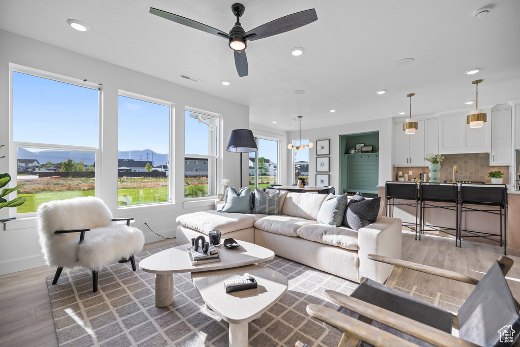 Living room featuring light wood-style flooring, recessed lighting, ceiling fan, a mountain view, and baseboards