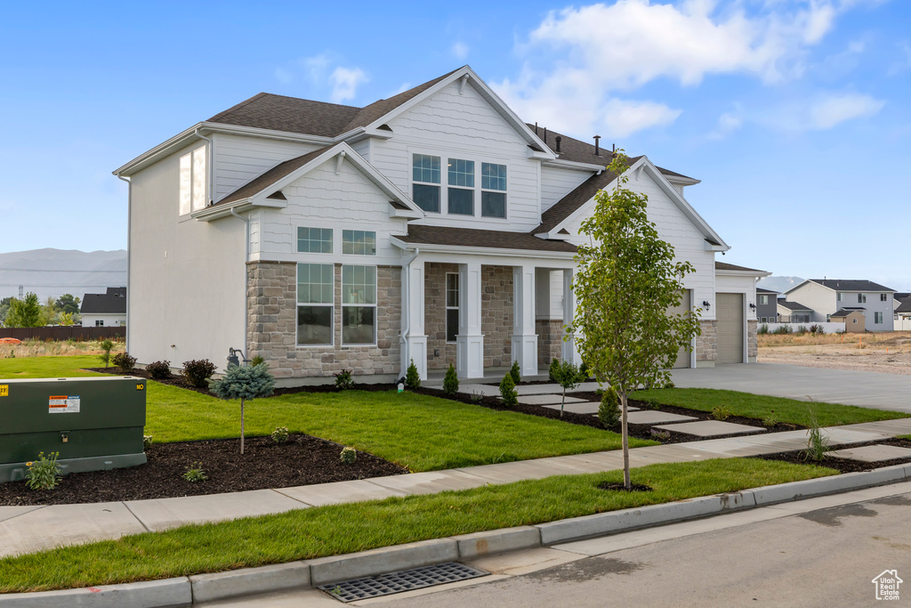 Craftsman-style home with driveway, stone siding, a front lawn, roof with shingles, and a garage