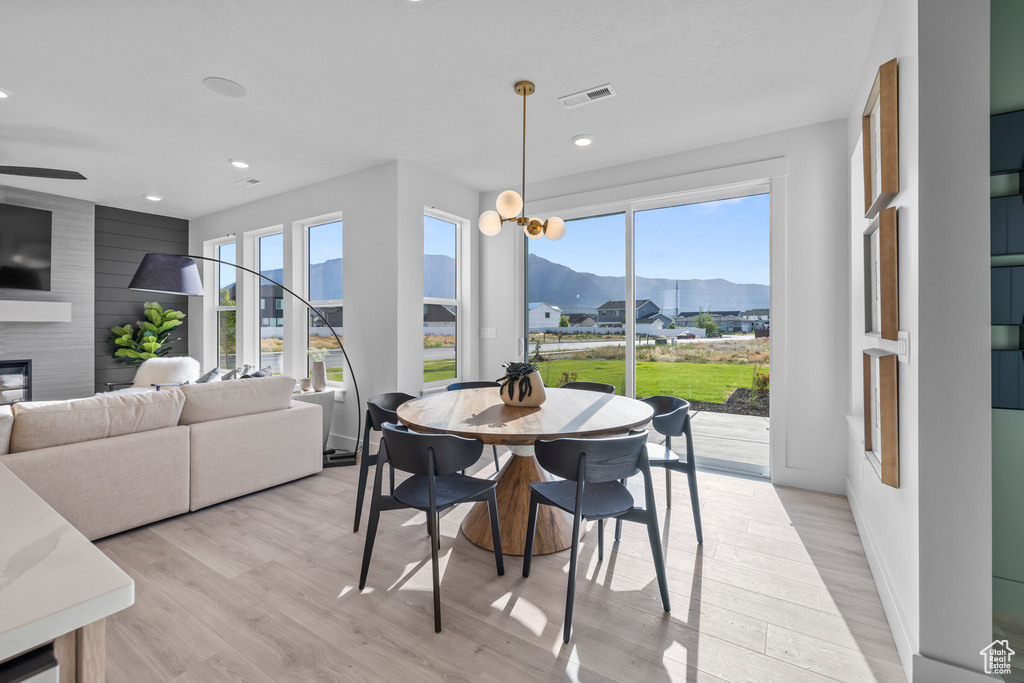 Dining area featuring a mountain view, light wood-style floors, recessed lighting, a large fireplace, and ceiling fan