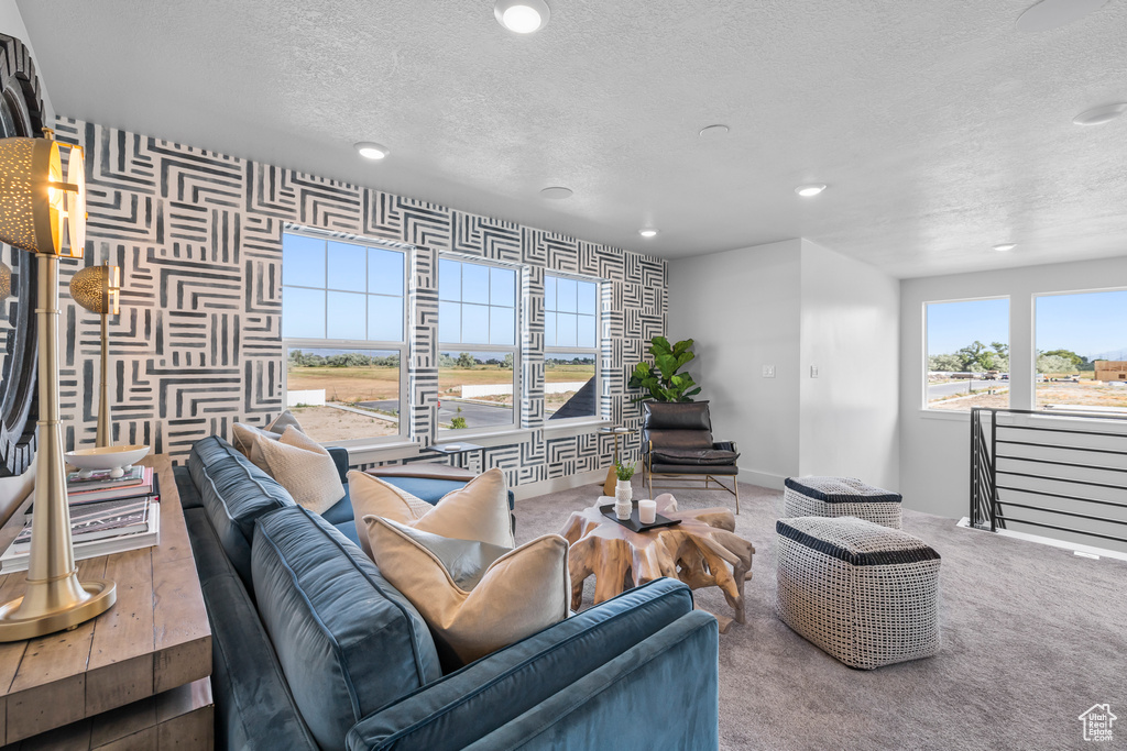 Living room featuring a textured ceiling, recessed lighting, carpet flooring, wallpapered walls, and baseboards