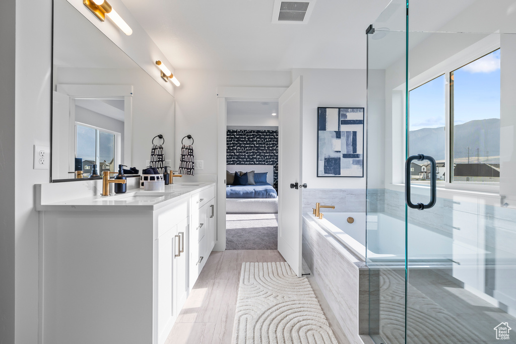 Full bath with ensuite bathroom, vanity, healthy amount of natural light, and a bath