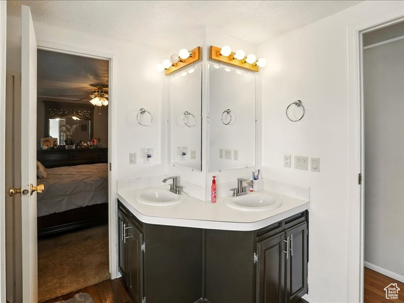 Ensuite bathroom with double vanity, wood finished floors, and ceiling fan
