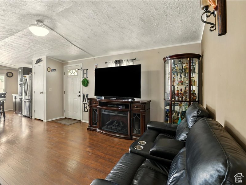 Living area with a textured ceiling, wood finished floors, and ornamental molding
