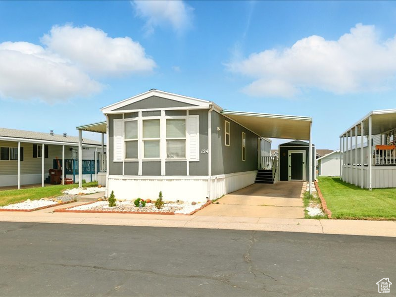 Manufactured / mobile home featuring driveway, an attached carport, and a sunroom