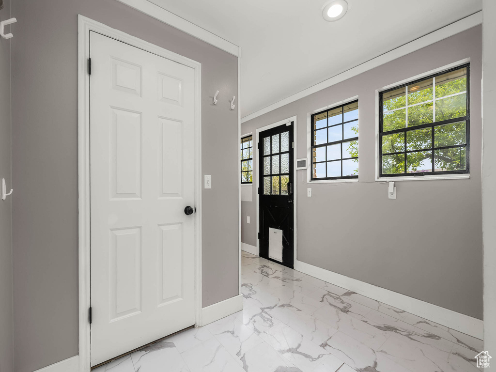 Entryway with baseboards, light marble finish floors, recessed lighting, and ornamental molding