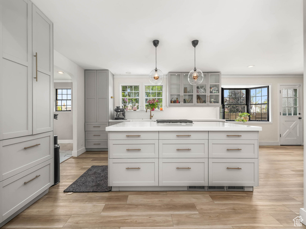 Kitchen with glass insert cabinets, baseboards, gray cabinetry, light countertops, and recessed lighting