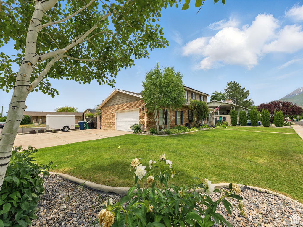 View of front of house featuring brick siding, a front lawn, driveway, and an attached garage