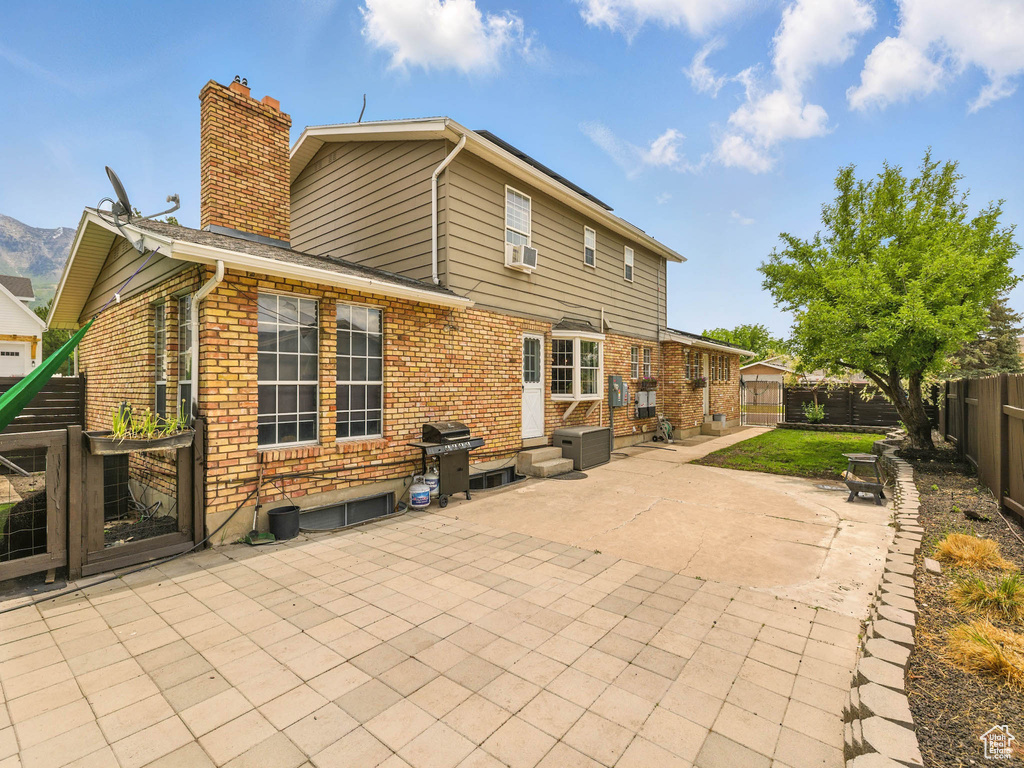Back of house with a chimney, a patio, brick siding, and a fenced backyard