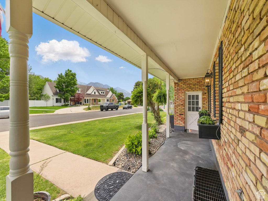 Covered porch with a lawn, a residential view, and a mountain view