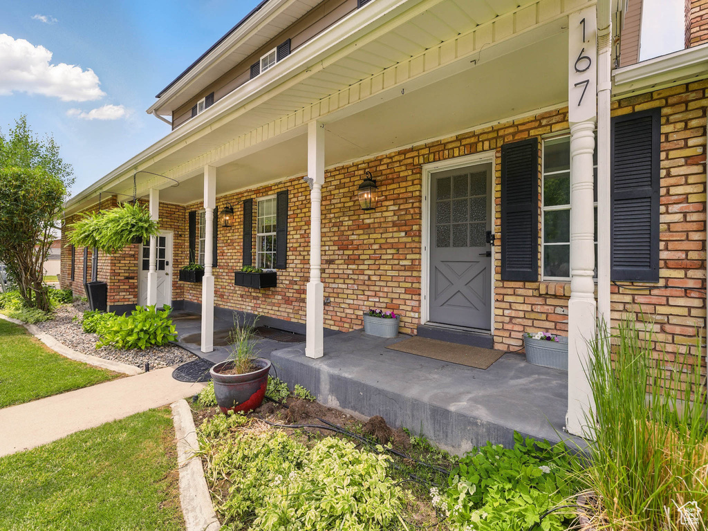 Entrance to property featuring a porch and brick siding