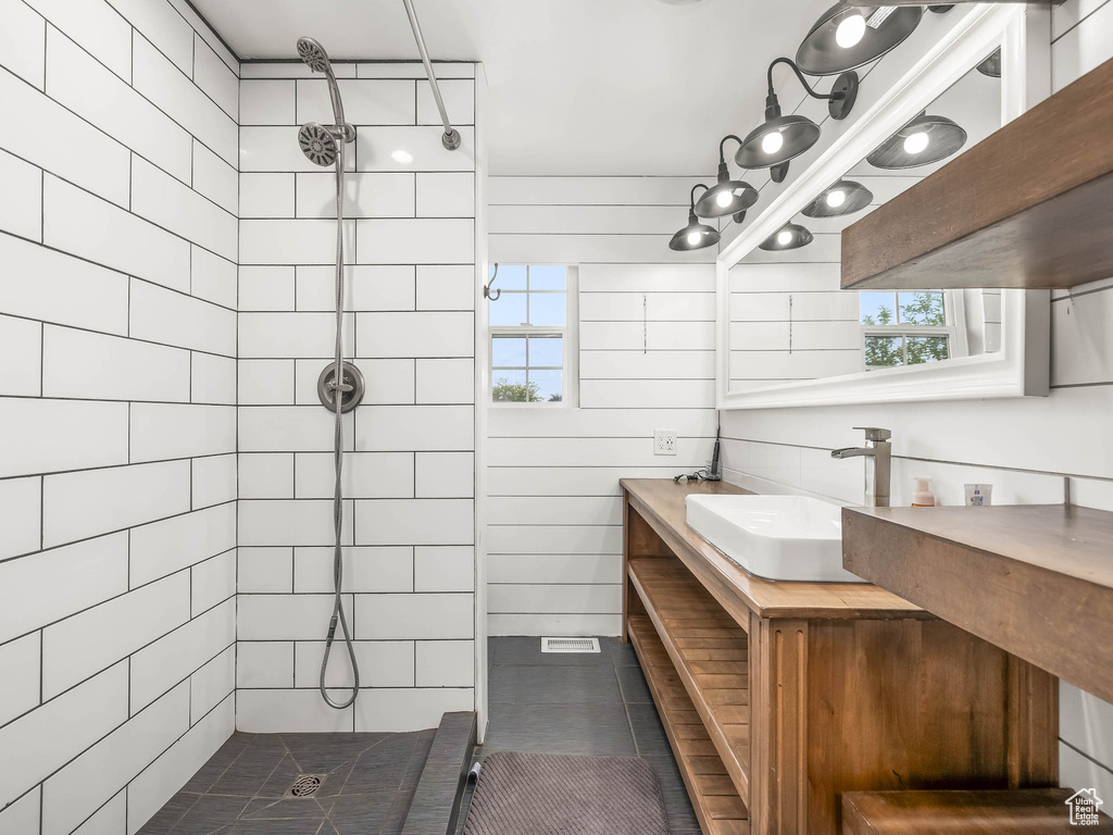 Full bath featuring tiled shower, healthy amount of natural light, vanity, and tile patterned flooring
