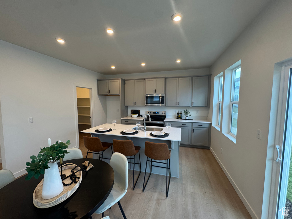 Kitchen with stainless steel microwave, gray cabinets, range with electric cooktop, light wood-style flooring, and recessed lighting
