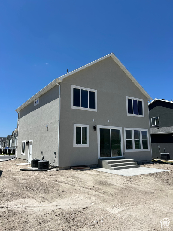 Back of house with stucco siding, entry steps, and central AC unit