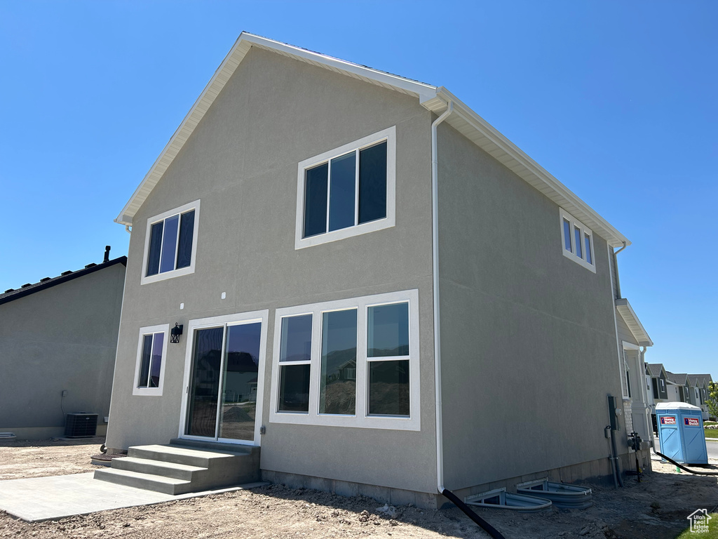 Rear view of house featuring cooling unit and stucco siding