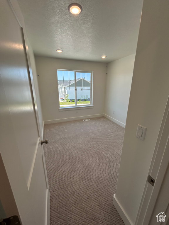 Carpeted spare room featuring baseboards, a textured ceiling, and recessed lighting