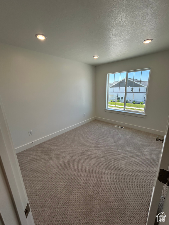 Empty room with recessed lighting, baseboards, carpet flooring, and a textured ceiling