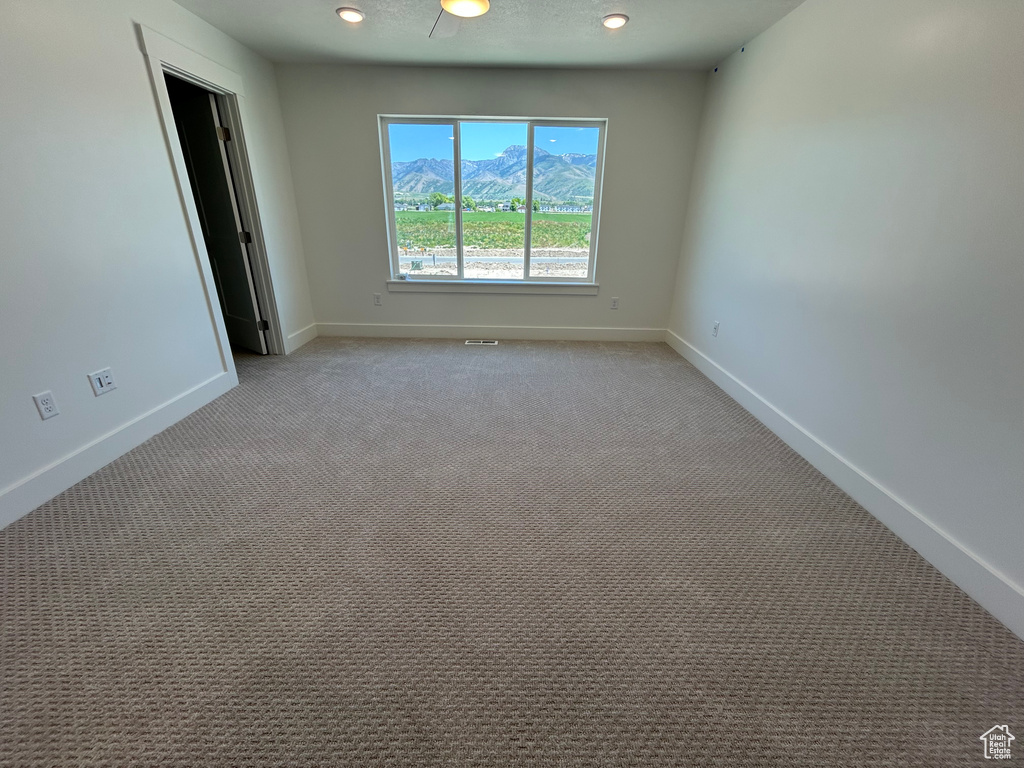 Unfurnished room featuring baseboards, light carpet, and a mountain view