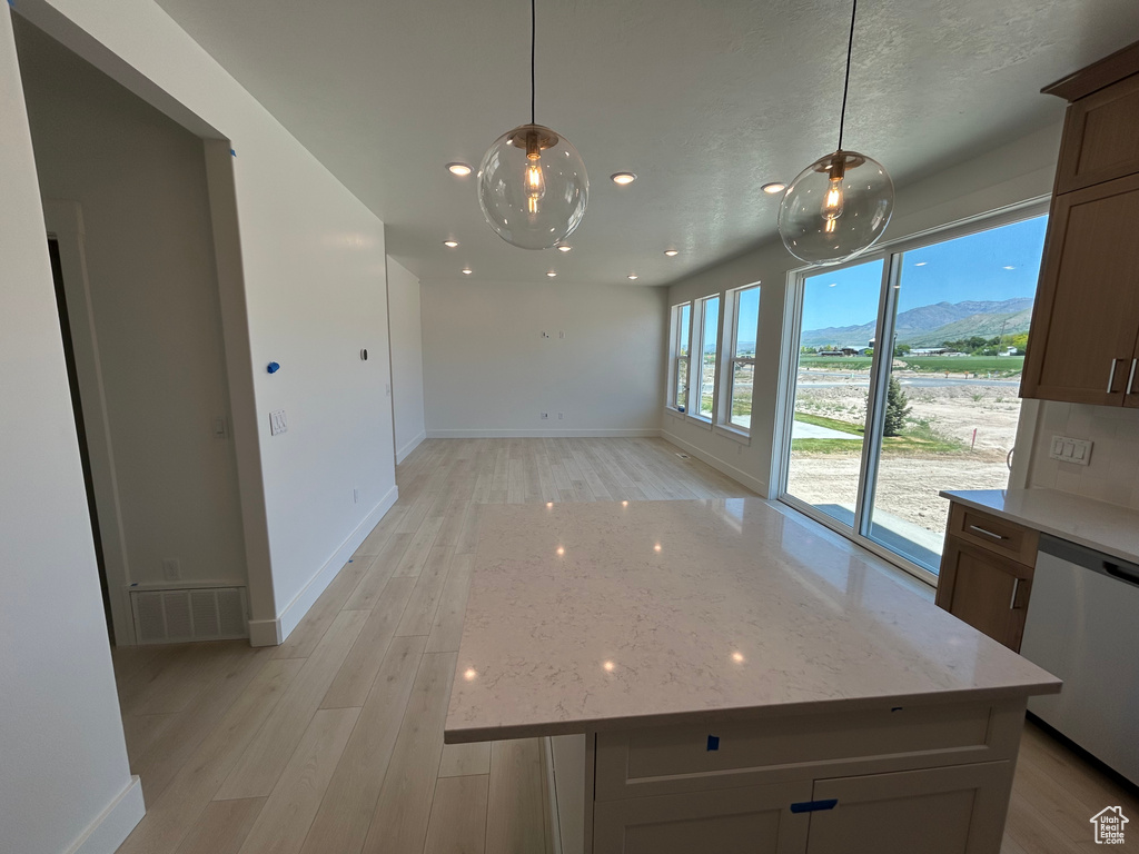 Unfurnished dining area featuring light wood-style flooring, baseboards, a mountain view, and recessed lighting