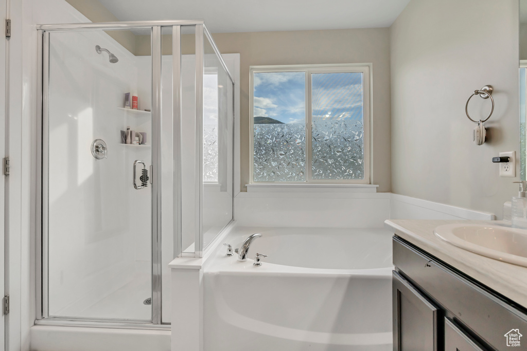 Full bathroom featuring a stall shower, a garden tub, and vanity