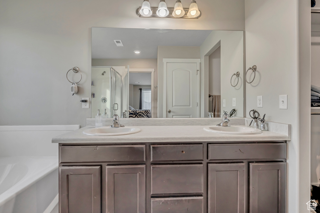 Bathroom featuring a bath, double vanity, and an enclosed shower