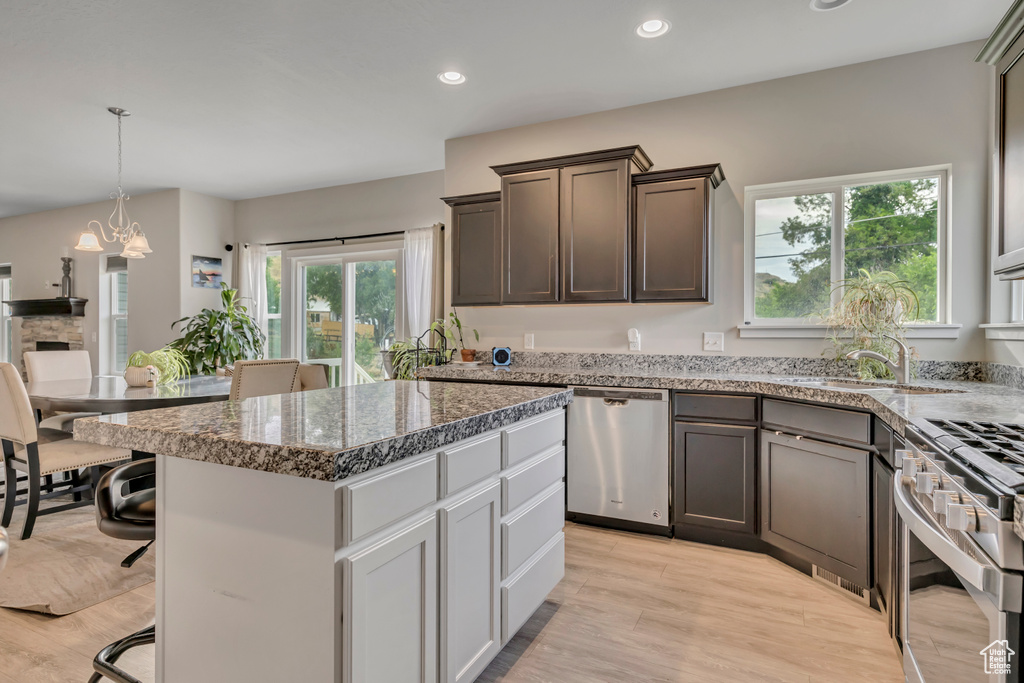 Kitchen featuring stainless steel appliances, a breakfast bar, light wood finished floors, a center island, and recessed lighting