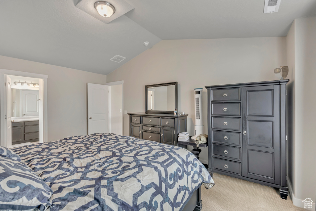 Bedroom featuring vaulted ceiling, light carpet, and ensuite bath