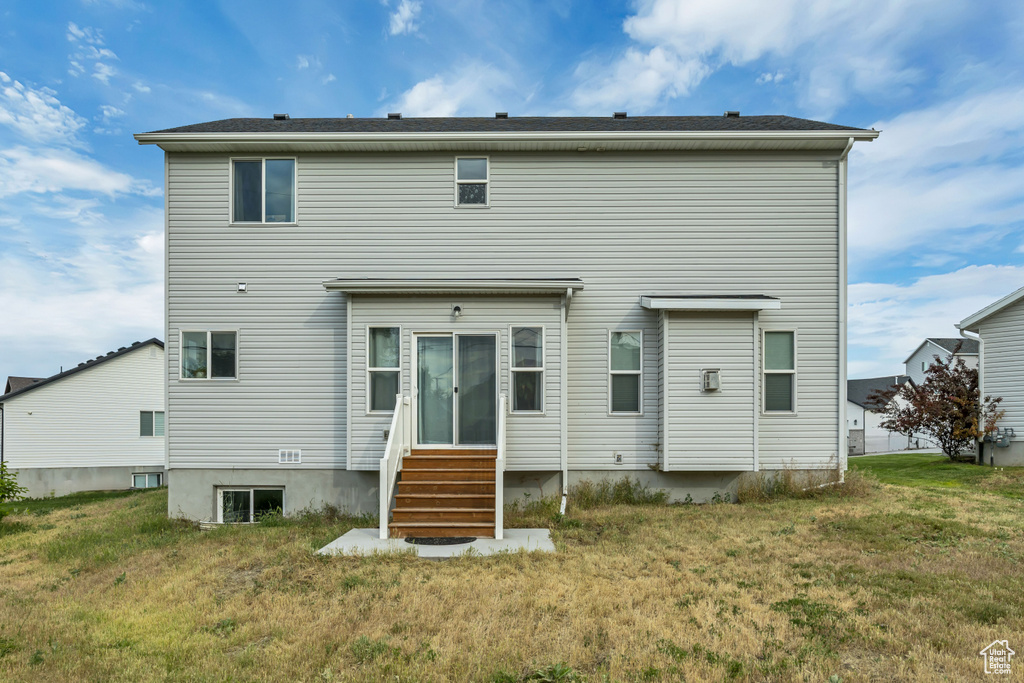 Back of property with entry steps and a lawn
