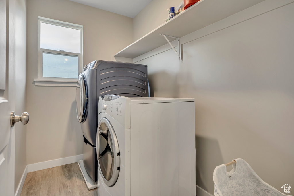 Laundry room with washing machine and clothes dryer and light wood-type flooring