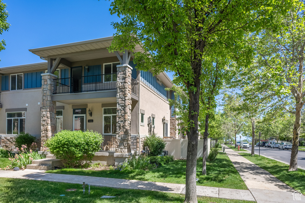 View of front of home featuring a balcony, stucco siding, and stone siding