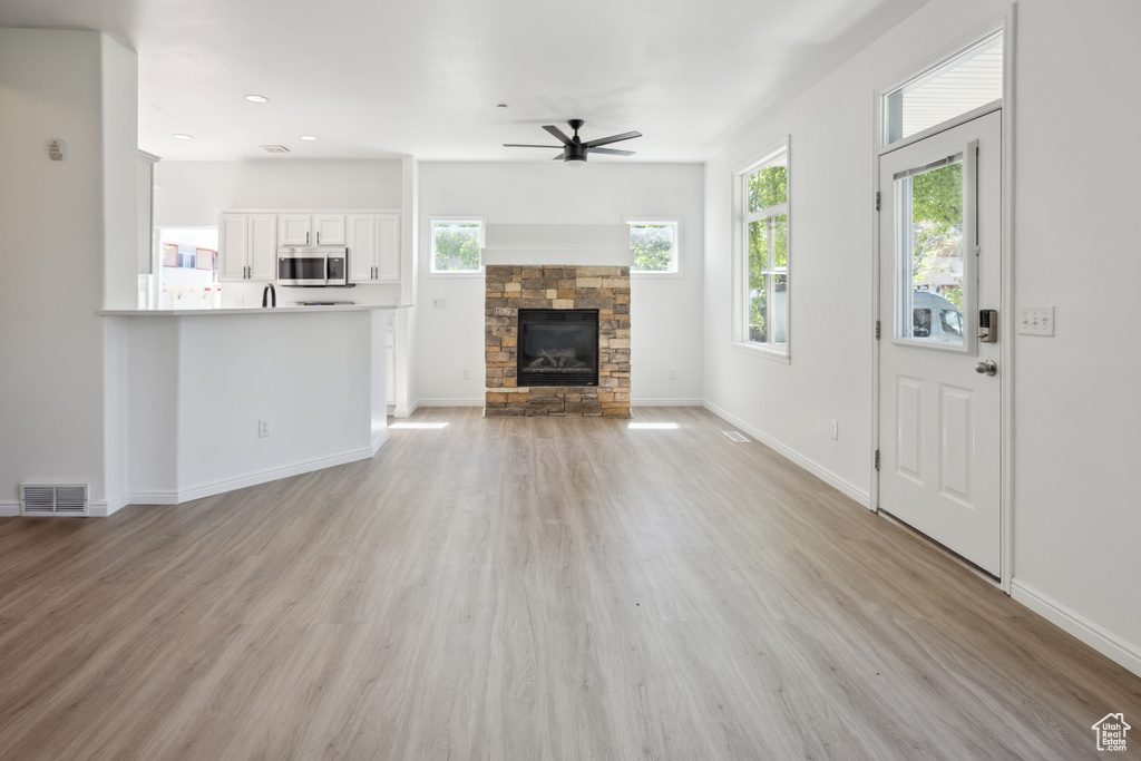Unfurnished living room featuring ceiling fan, light wood finished floors, a fireplace, baseboards, and recessed lighting