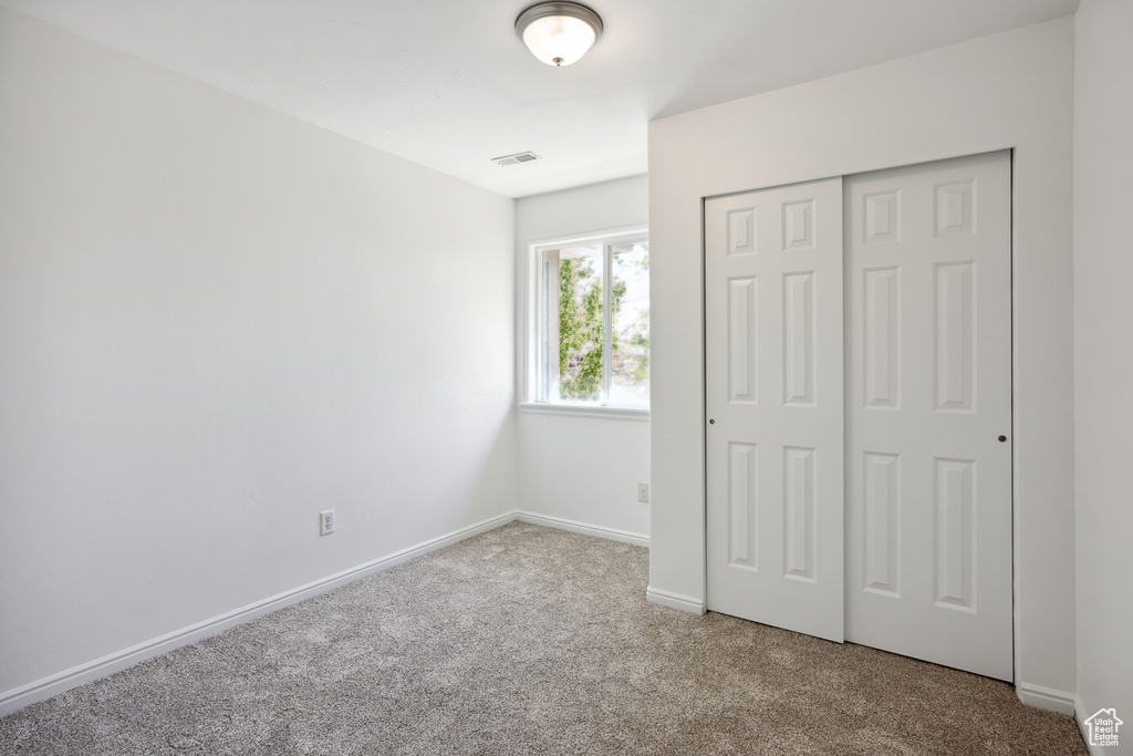 Unfurnished bedroom with carpet floors, a closet, and baseboards