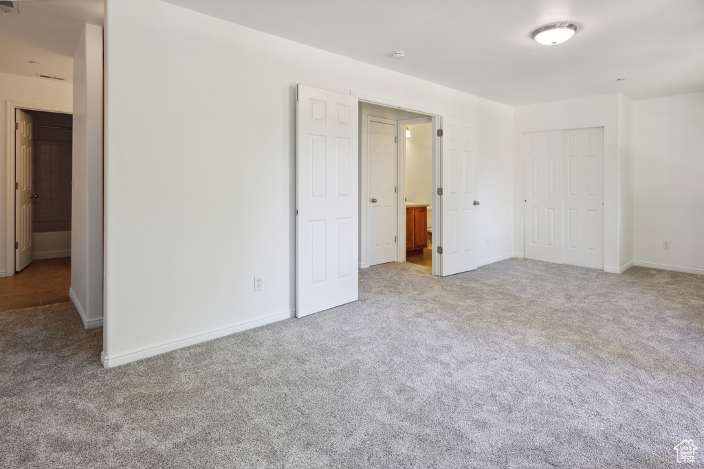 Unfurnished bedroom featuring carpet floors, baseboards, a closet, and ensuite bathroom