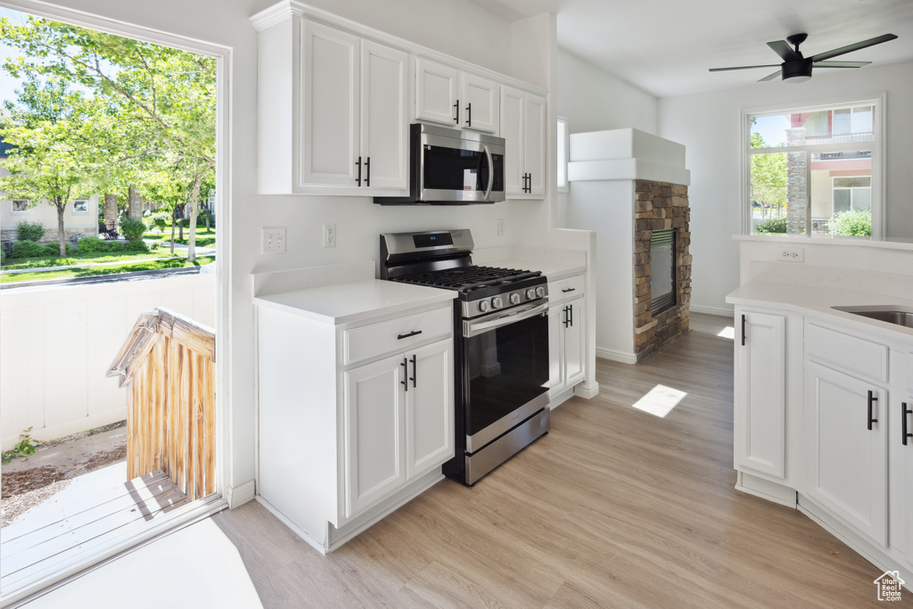 Kitchen featuring appliances with stainless steel finishes, light wood-style floors, light countertops, and ceiling fan