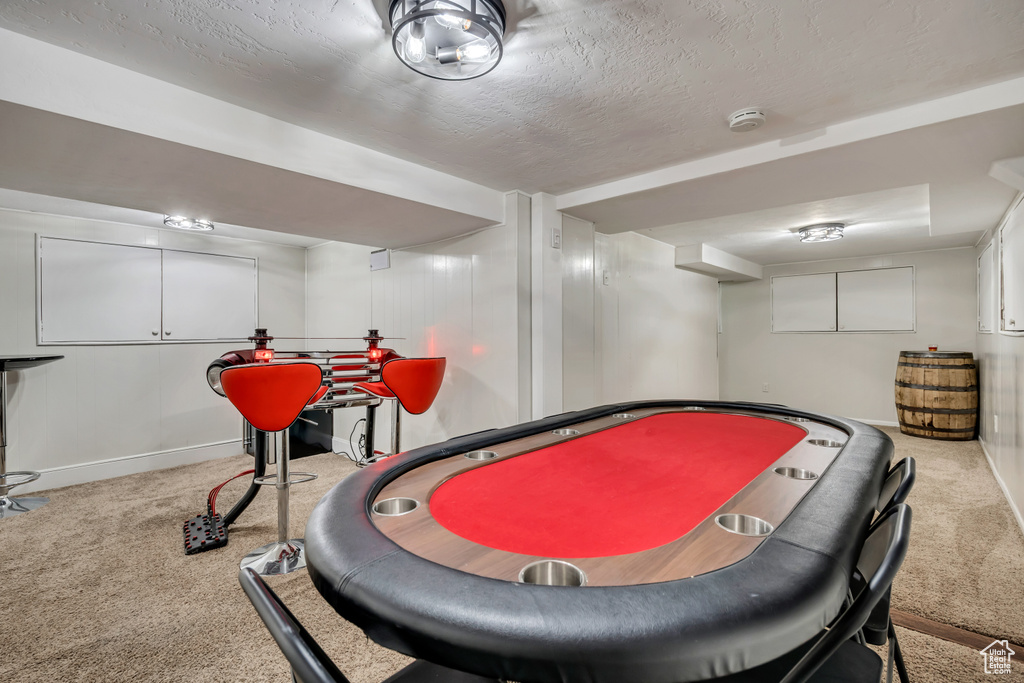 Recreation room featuring carpet flooring, baseboards, and a textured ceiling