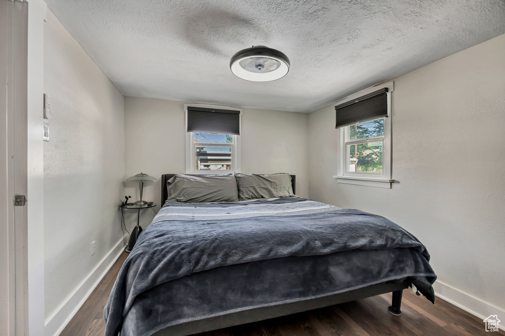 Bedroom featuring baseboards, a textured ceiling, and wood finished floors