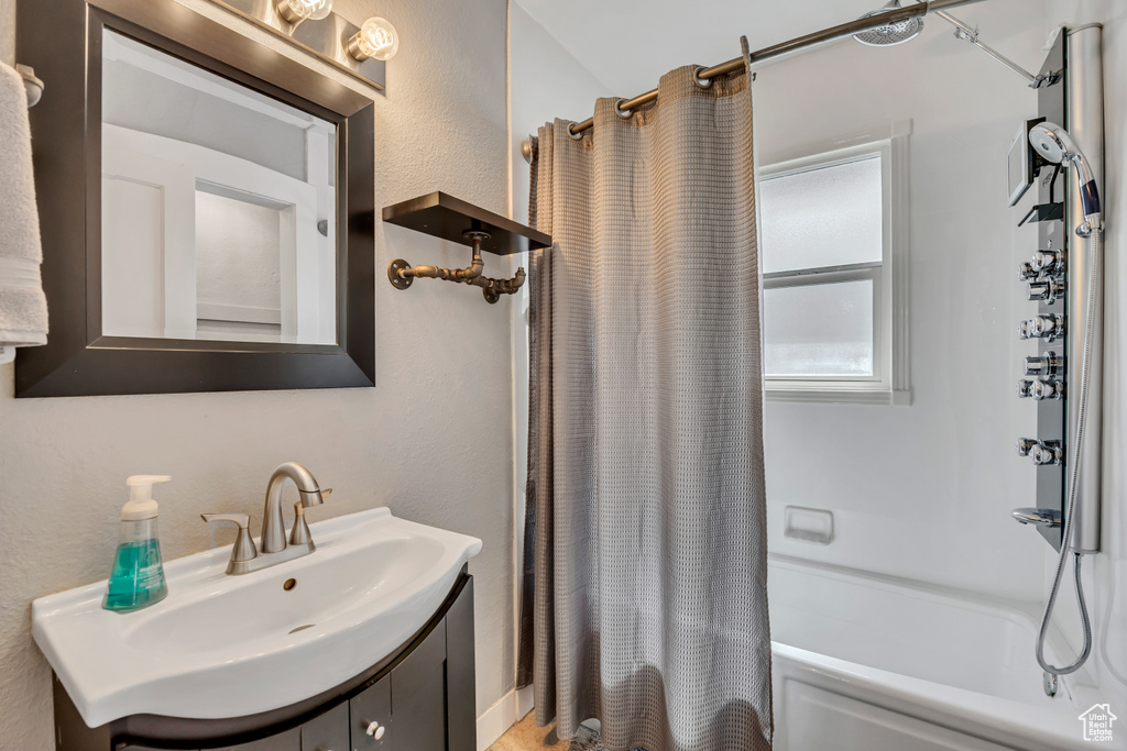 Bathroom with shower / bathtub combination with curtain and vanity