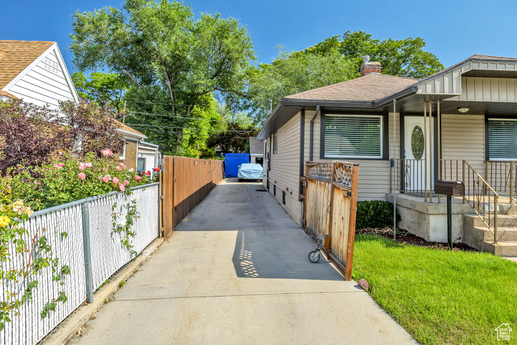 View of front of property featuring driveway, a chimney, and roof with shingles