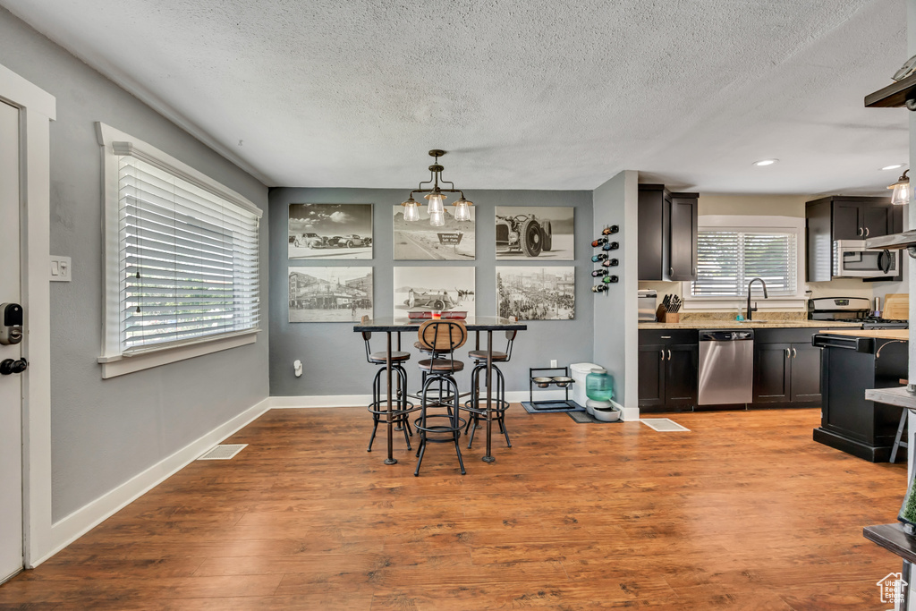 Dining room with a textured ceiling, wood finished floors, baseboards, and recessed lighting