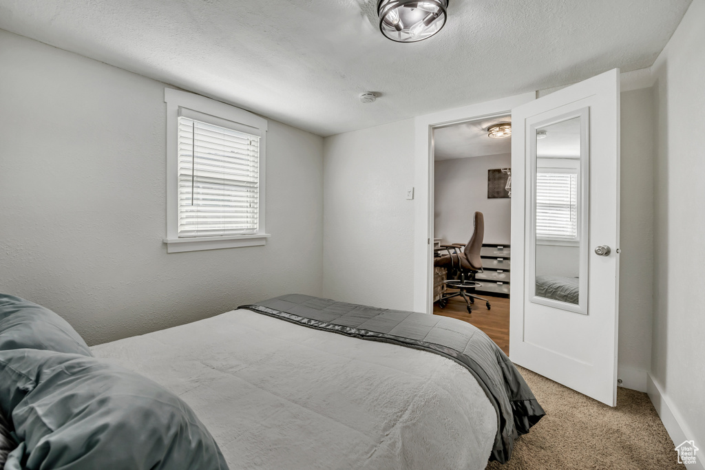 Bedroom with multiple windows, a desk, and carpet floors